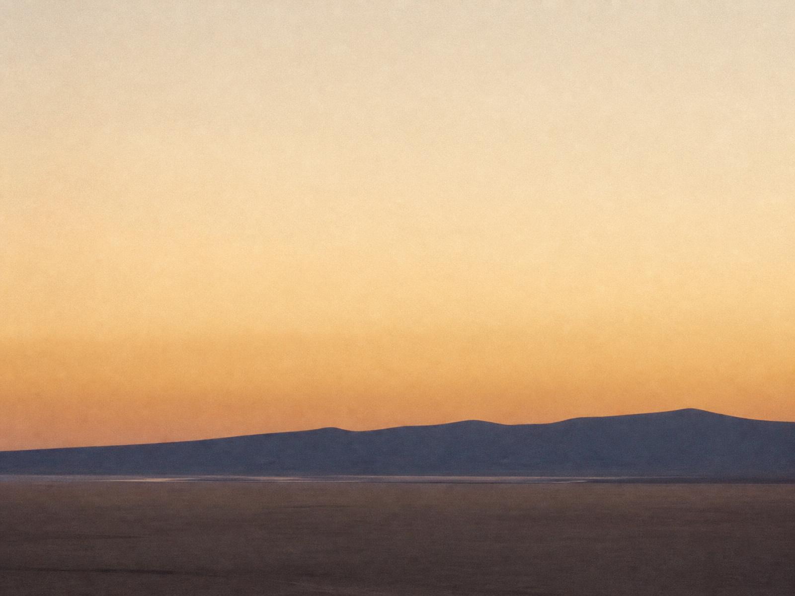 Quiet horizon at dawn, warm light meeting a distant ridgeline